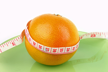 a grapefruit with a measure tape wrapped around it の写真素材