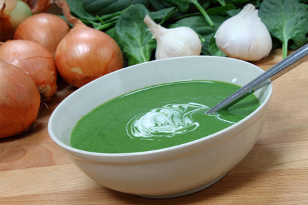 A nutritious bowl of fresh spinach soup, with some of the ingreadients behind の写真素材