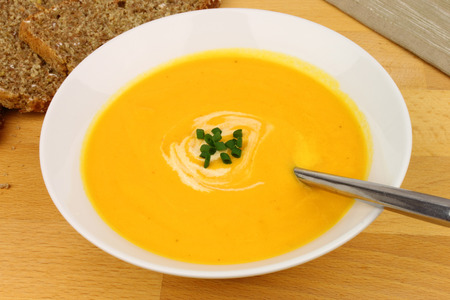 A bowl of homemade, roasted butternut squash soup with wholemeal brown bread の写真素材
