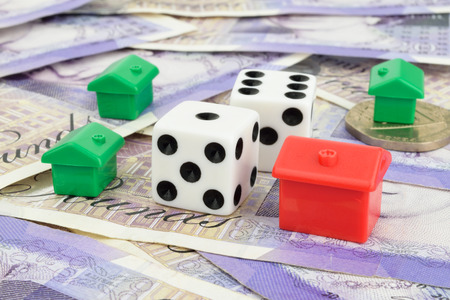 Toy houses surrounding two dice on Sterling money  A metaphor on property risk and finance の写真素材