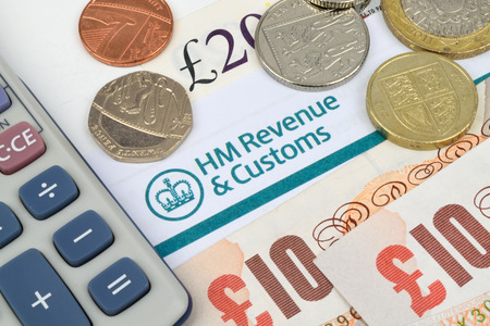 A close up of HM tax return with coins and a calculator.の写真素材