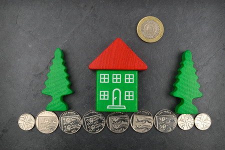 A toy house on Sterling coins and on a slate background.の写真素材