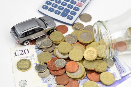 A motor finance still life with car, calculator, coins, notes and a jar.の写真素材