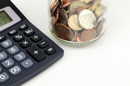 A jar of Sterling coins ans a calculator to represent Sterling finance.の写真素材