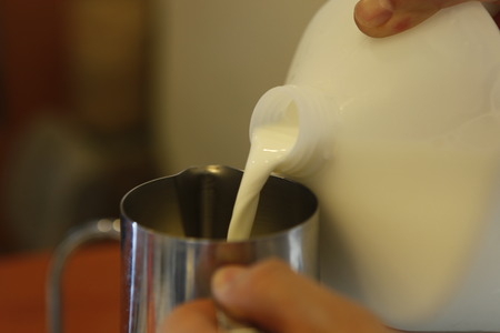 Midsection of barista making cappuccino at counter in coffeeshopの写真素材