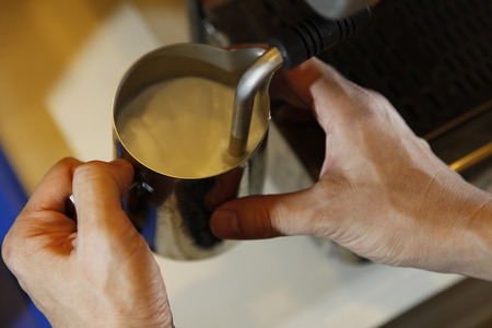 Midsection of barista making cappuccino at counter in coffeeshopの写真素材