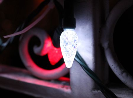 A single Christmas lights lightbulb with ornate fence in the backの写真素材