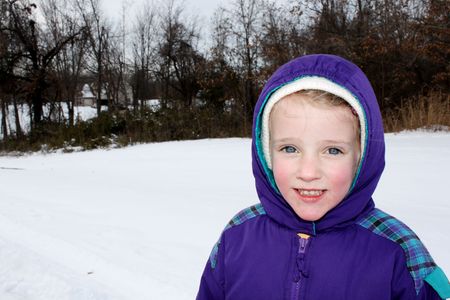 Happy child with snow in the backgroundの写真素材