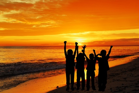 Children silhouettes on a  sunset beachの写真素材