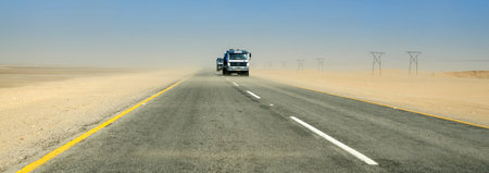 SWAKOMPUND, NAMIBIA - OCTOBER 31 2013: In a year of drought goods vehicle drives through a sand storm through the Namib desert at Swakompmund, Namibia, Africaのeditorial素材