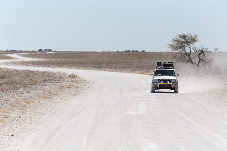ETOSHA, NAMIBIA - OCTOBER 27 2013: Safari Truckdrives on dusty road in a year of drought at Etosha National Park, Namibia, Africaのeditorial素材