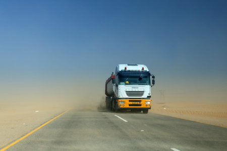 SWAKOMPUND, NAMIBIA - OCTOBER 31 2013: In a year of drought goods vehicle drives through a sand storm through the Namib desert at Swakompmund, Namibia, Africaのeditorial素材