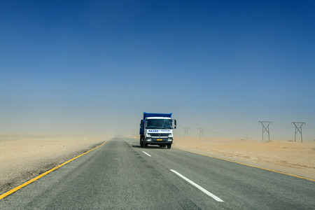SWAKOMPUND, NAMIBIA - OCTOBER 31 2013: In a year of drought goods vehicle drives through a sand storm through the Namib desert at Swakompmund, Namibia, Africaのeditorial素材