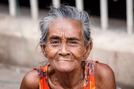 YANGON, MYANMAR - JUNE 12 2015: Older lady sits on the street on one of the hottest recorded days before monsoon season in Yangon, Myanmar.のeditorial素材