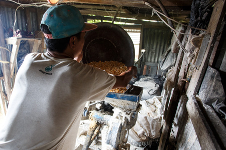 FALAM, MYANMAR - JUNE 17 2015: Making pig feed using a grinding machine in the town of Falam in Chin State, Myanmar.のeditorial素材