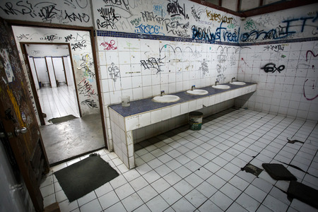 An urban ghetto washroom / restroom with dirty grungy graffiti wallsのeditorial素材