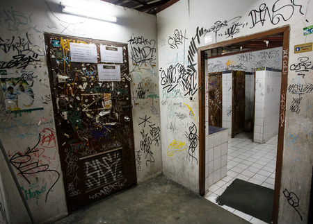 An urban ghetto washroom / restroom with dirty grungy graffiti wallsのeditorial素材