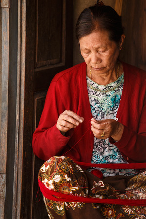 CHIN STATE, MYANMAR - JUNE 18 2015: Lady weaving with wool in the recently opened for tourists Chin State Mountainous Region, Myanmar (Burma)のeditorial素材