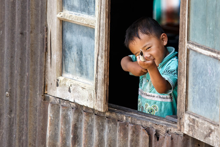 CHIN STATE, MYANMAR - JUNE 18 2015: Cute young boy in window in the recently opened for tourists Chin State Mountainous Region, Myanmar (Burma)のeditorial素材