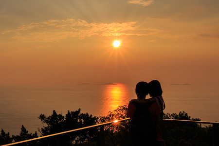 Silhouette mom hold her dougther over sunset background.の写真素材