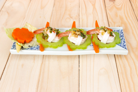 boiled shrimp, squid and vegetable topping with spicy seafood sauce on wooden backgroundの写真素材