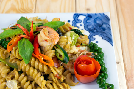 macaroni fried with spicy seafood (shrimp and squid) on wooden backgroundの写真素材