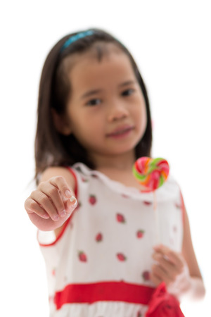 A little girl show her teeth, she surrenders to sweet candy. selective focus on blur background.の写真素材