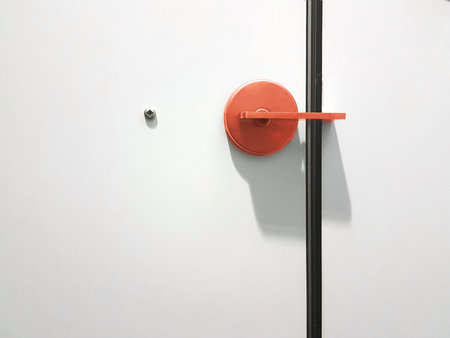 red door knob on white door with a screw