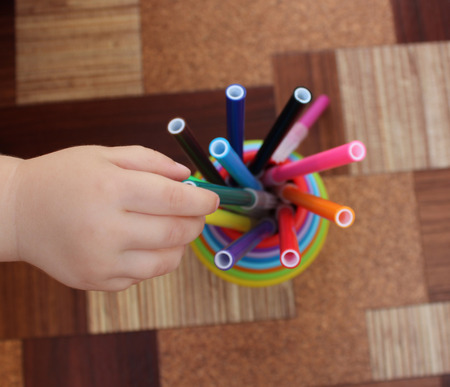 children's hands, taking multicolored felt pens in plastic cupsの写真素材