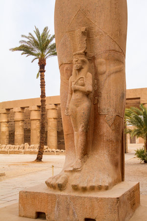Statue of a small Pharaoh beneath the feet of a larger statue, Karnak temple, Luxor, Egyptの写真素材