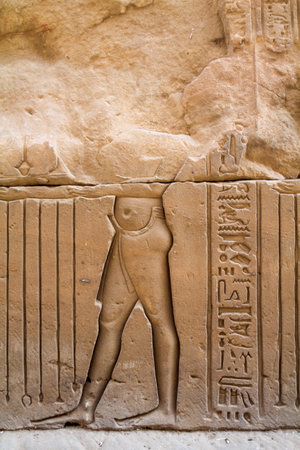 Damaged ancient relief of a person, hieroglyphs at the side, Egyptian Horus temple in Edfuの写真素材