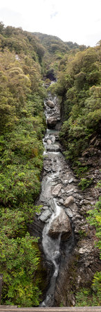 Vertical panoramic view of mountain stream flowing into glacial valley of Franz Josef Glacier National Park, New Zealandの写真素材
