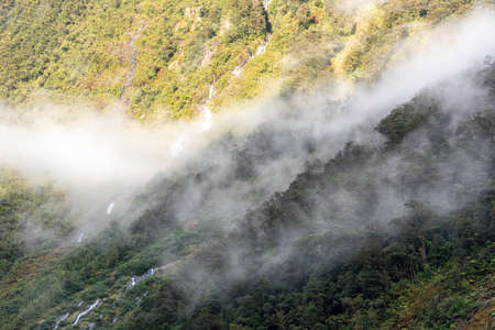A new morning dawning at Doutful Sound, clouds hanging low in the mountains, South Island of New Zealandの写真素材