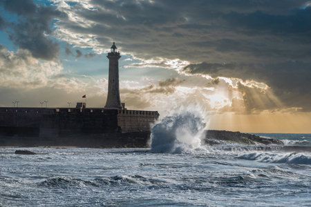 Scenic sunset over the atlantic ocean, a lighthouse at the shore of Morocco, waves break at the...
