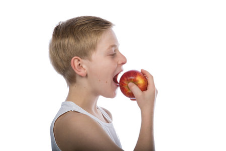 a young boy is eating a red apple isolated on white backgroundの写真素材