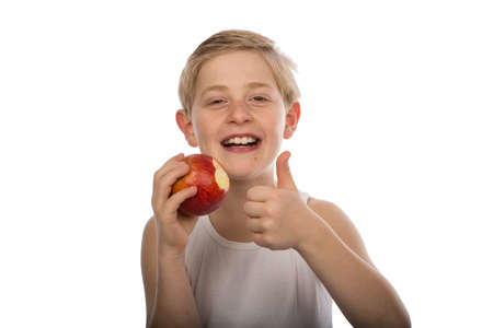 a smiling young boy with a red apple isolated on white backgroundの写真素材