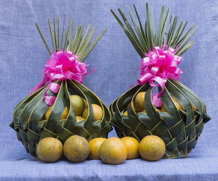 Orange in two Coconut leaves basket on purple clothの写真素材