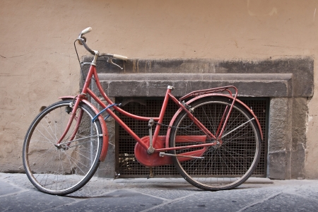 An old red bike laid on a wallの写真素材