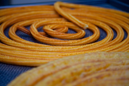 Recently baked Spanish churro on its original form before cutting the wheel into small sticks of about 5 inches per stick.  A Churro (singular) is a fried-dough pastry that is eaten by dipping it into a cup of hot and creamy chocolate making the perfect cの写真素材