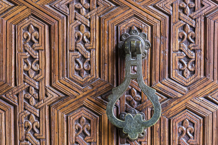 Iron Moroccan door knob on a traditionally carved wooden door (horizontal shot).の写真素材