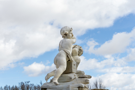 Medieval statue of cupids against of white clouds on skyの写真素材