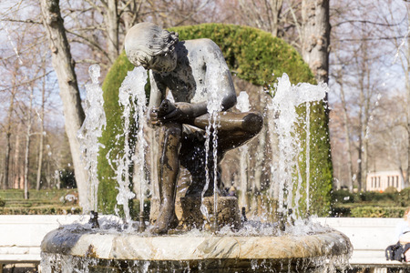 View of ancient fountain with worn-out marble boy looking at his feet in the middle. Sunny.の写真素材