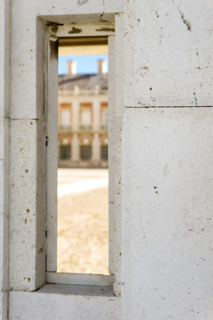 Close-up of marble wall with geometric window with view of sunlit buildingの写真素材