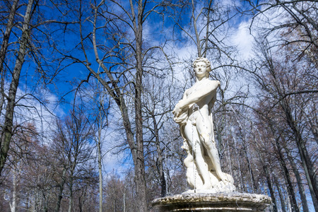 Marble statue of naked man on top of medieval fountain against of leafless treesの写真素材