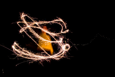 A young woman playing with sparklers at night.の写真素材