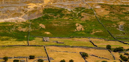 A small stone building in an English field, surrounded by small stone walls.の写真素材