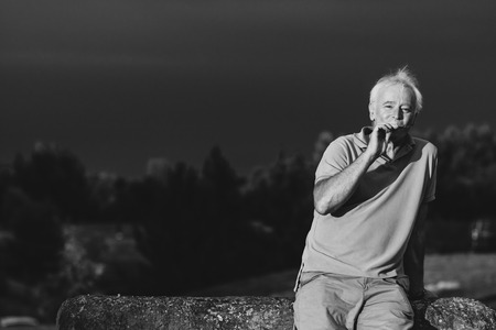 A handsome older man puffing on an e-cigarette in black and whiteの写真素材