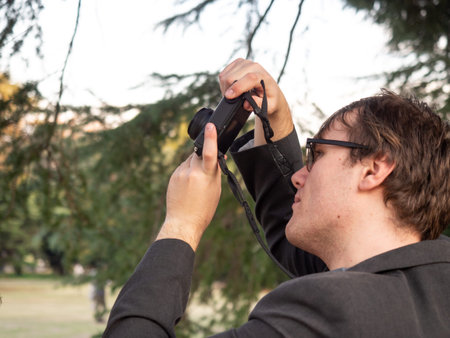 A man taking pictures in the park on his compact digital camera