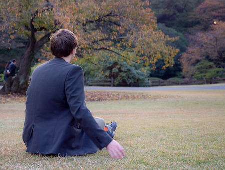 A man sat relaxing in a park at Autumnの写真素材