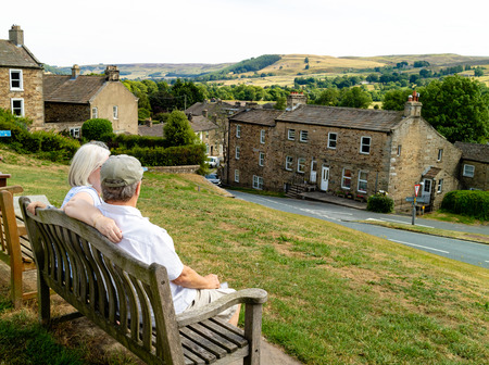 An elderly couple snuggling together on a bench, enjoying their retirement in the Yorkshire Dales on holidayの写真素材